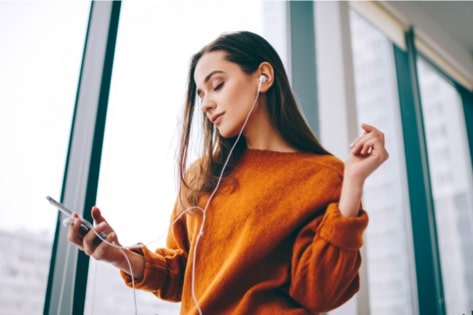 A woman with headphones dances using an entertainment app