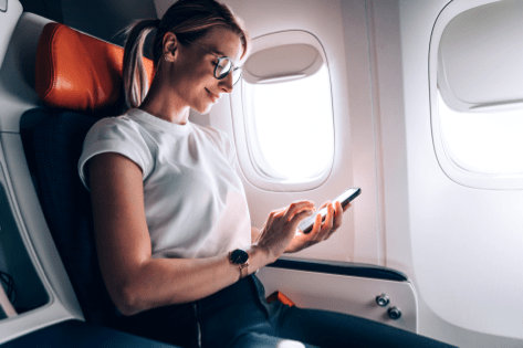Woman on plane using travel mobile app